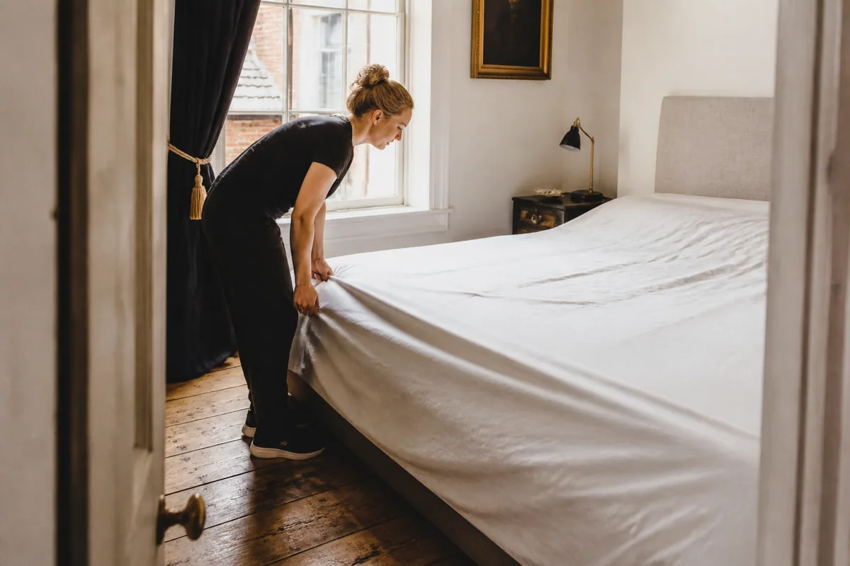 Cleaner preparing a bed in a York townhouse